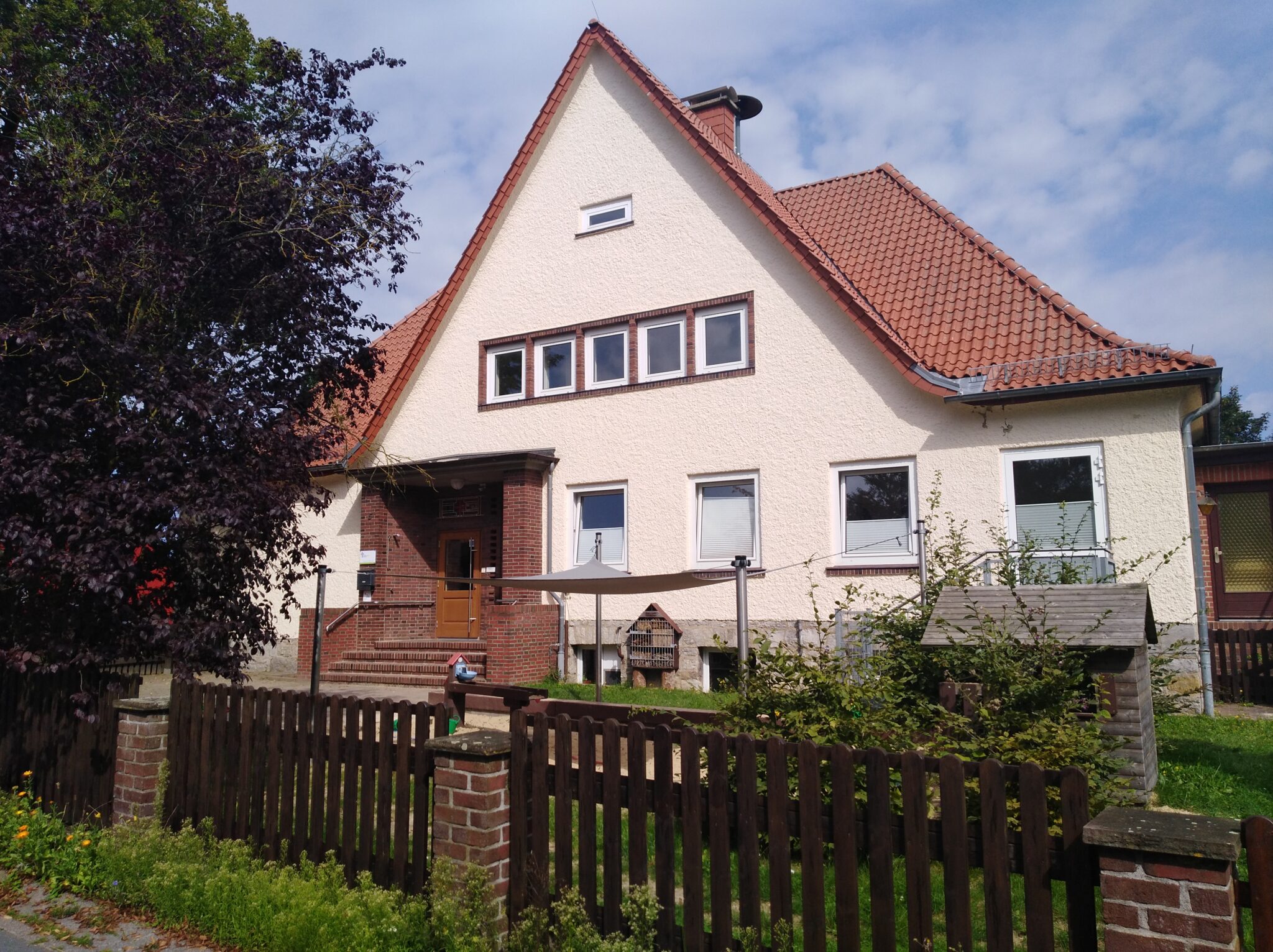 Die Kindertagesstätte "Bergzwerge", ein gemütliches Gebäude mit einem grünen Garten und einem Spielplatz im Vordergrund.